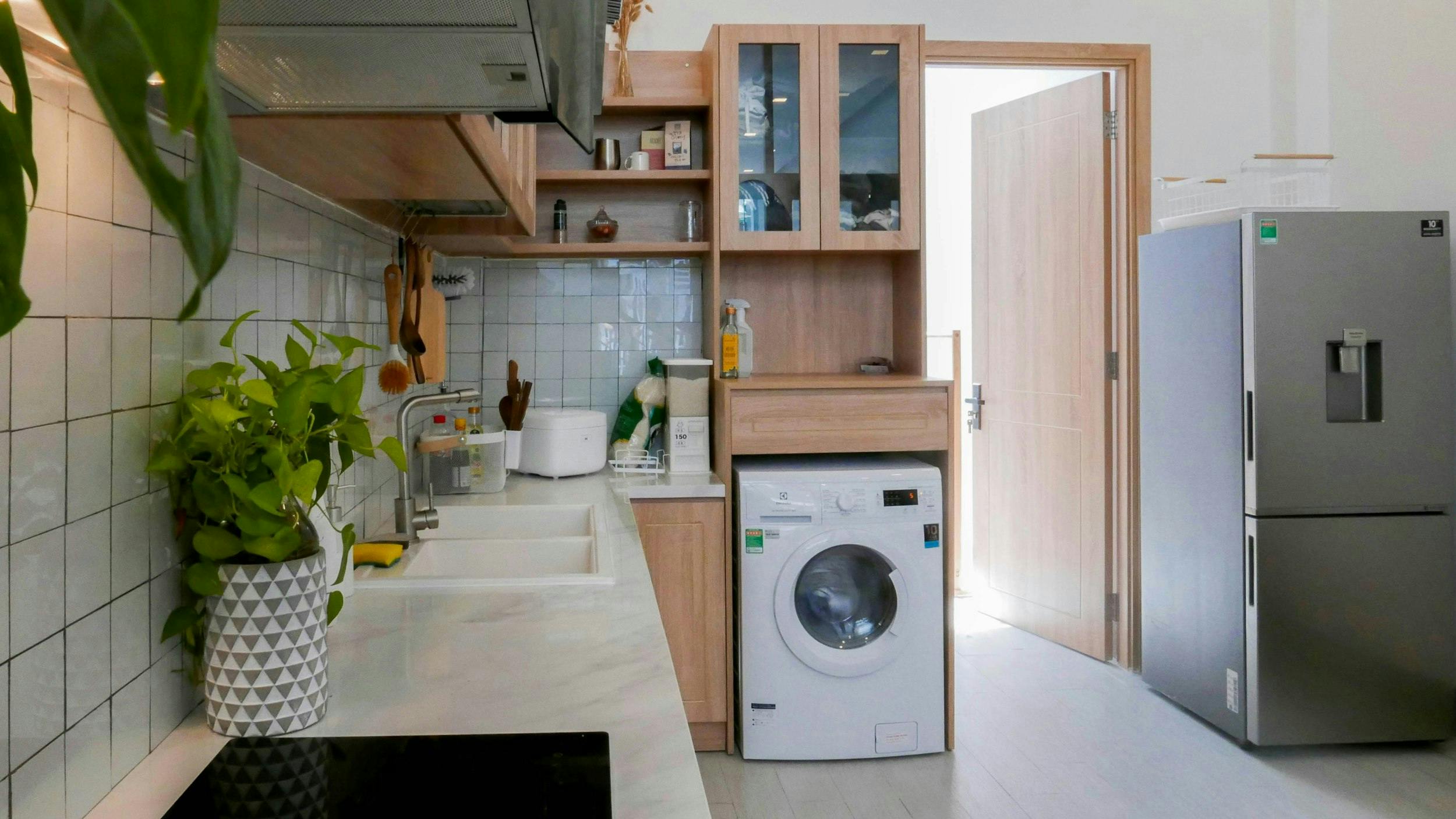White washing machine in kitchen with fridge.
